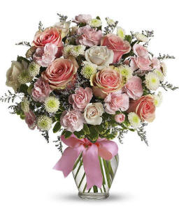 Pink and white roses with green accents in a clear glass vase