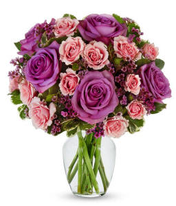 Lavender and pink bouquet with greenery arranged in a clear glass vase
