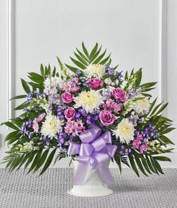 A heartfelt sympathy floor basket featuring white roses, white snapdragons, lavender stock, lavender mums, and white Monte Casino.
