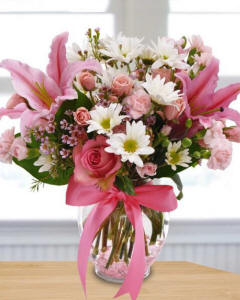 Pink Sonnet-Lovely mini pink carnations, pink spray roses, pink roses, stargazer lilies, white daisy poms, waxflower, lemon leaf, arranged in a ginge jar vase wit a pink ribbon-floral arrangements