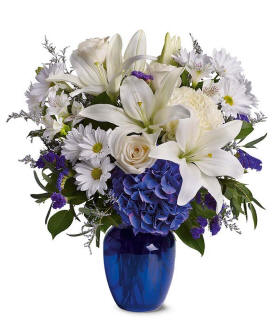Beautiful in Blue Bouquet with blue hydrangea, white roses, white oriental lilies, white alstroemeria, purple limonium, and purple statice in a blue glass vase