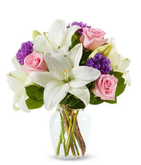 A clear vase with Easter lilies and pink roses