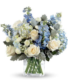 Faithful Guardian Bouquet with ivory roses, blue hydrangea, blue delphinium, white button poms, dusty miller, and greens in a clear cube vase