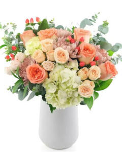 Feeling peachy-an abundance of roses, spray roses, hydrangea,cremon, and seasonla fillers arranged in a white ceramic vase- spring arrangements