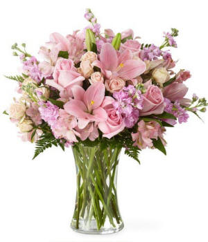 Pink lilies with pink and white roses in a tall clear vase, airy greenery and premium look