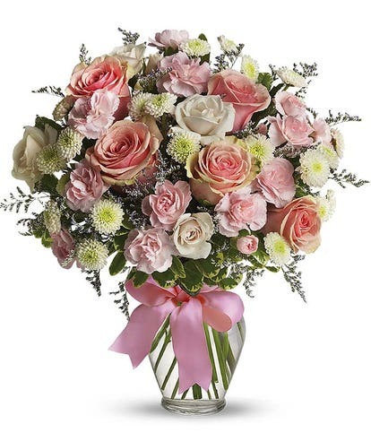 Cotton Candy bouquet with pink and white roses, mini carnations, and green poms in a clear glass vase with pink ribbon