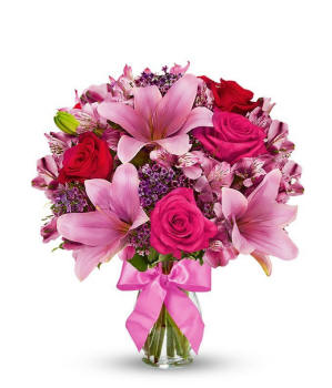 Red roses with pink lilies in a clear glass vase with a pink bow, romantic mixed bouquet