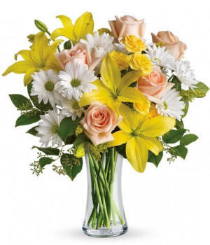 Yellow lilies with white daisies in a clear glass vase